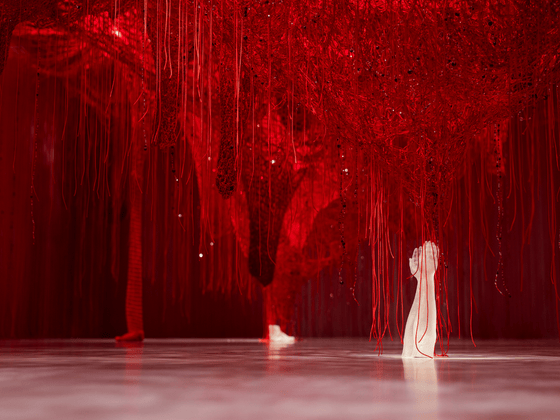 Wunderkammer Crystallizing Identity von Chiharu Shiota in den Swarovski Kristallwelten: Ein dichtes Netz aus roten Fäden mit eingearbeiteten Kristallen, aus dem eine weiße Kristallhand emporragt.