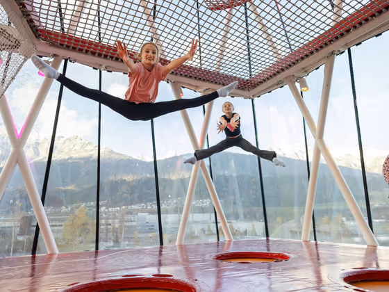 Kinder springen und toben im Spielturm der Swarovski Kristallwelten – Bewegung und Spaß mit Tiroler Bergpanorama im Hintergrund.