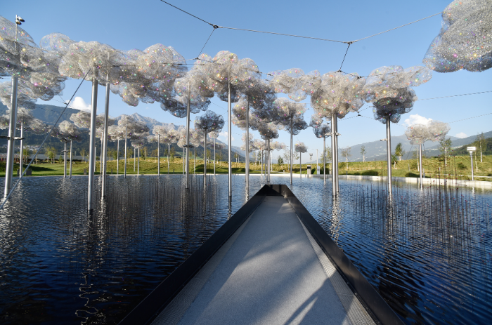 Kristallwolke mit funkelnden Kristallen über dem Spiegelwasser im Park der Swarovski Kristallwelten in Wattens, Tirol.