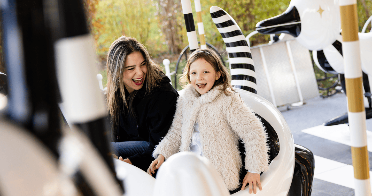 Mutter und Tochter genießen mit viel Freude eine Fahrt auf dem Karussell im Park der Swarovski Kristallwelten – eines von vielen unvergesslichen Erlebnissen mit der Jahreskarte.