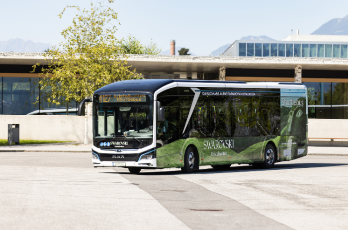 Modern e-shuttle bus with Swarovski Kristallwelten branding in front of the entrance area in Wattens — environmentally friendly travel for visitors.