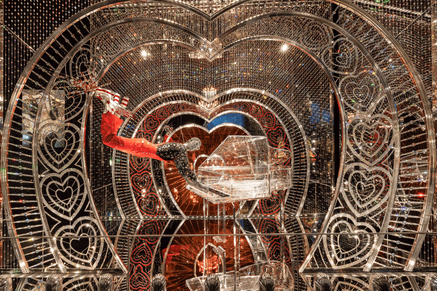 Nachgebildete Figur von Elton John, schwebend in rotem Anzug mit funkelndem Cape vor einem Kristallflügel, umrahmt von Herzornamenten und tausenden Kristallen in der Wunderkammer Art of Performance in den Swarovski Kristallwelten