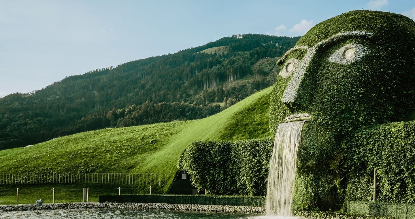 Der ikonische Riese mit leuchtenden Augen und Wasserfall in den Swarovski Kristallwelten Wattens, inmitten der Tiroler Berglandschaft.