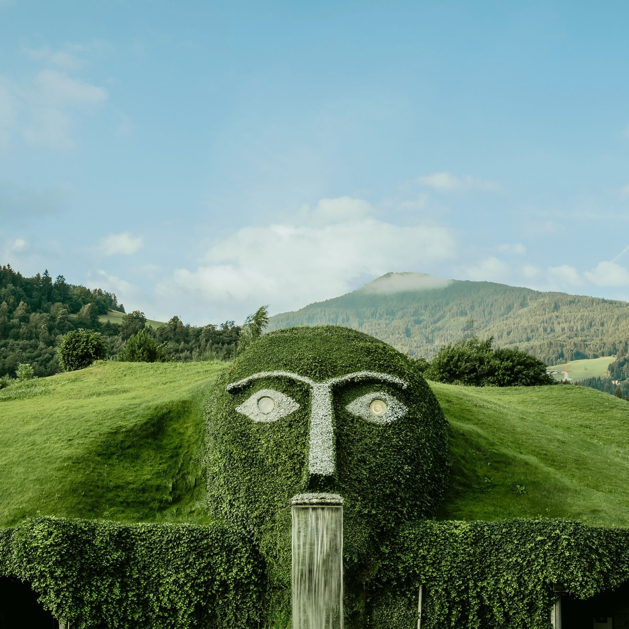 Der markante Riese mit leuchtenden Augen und Wasserfall ist das Herzstück der Swarovski Kristallwelten Wattens, umgeben von der Tiroler Bergkulisse.