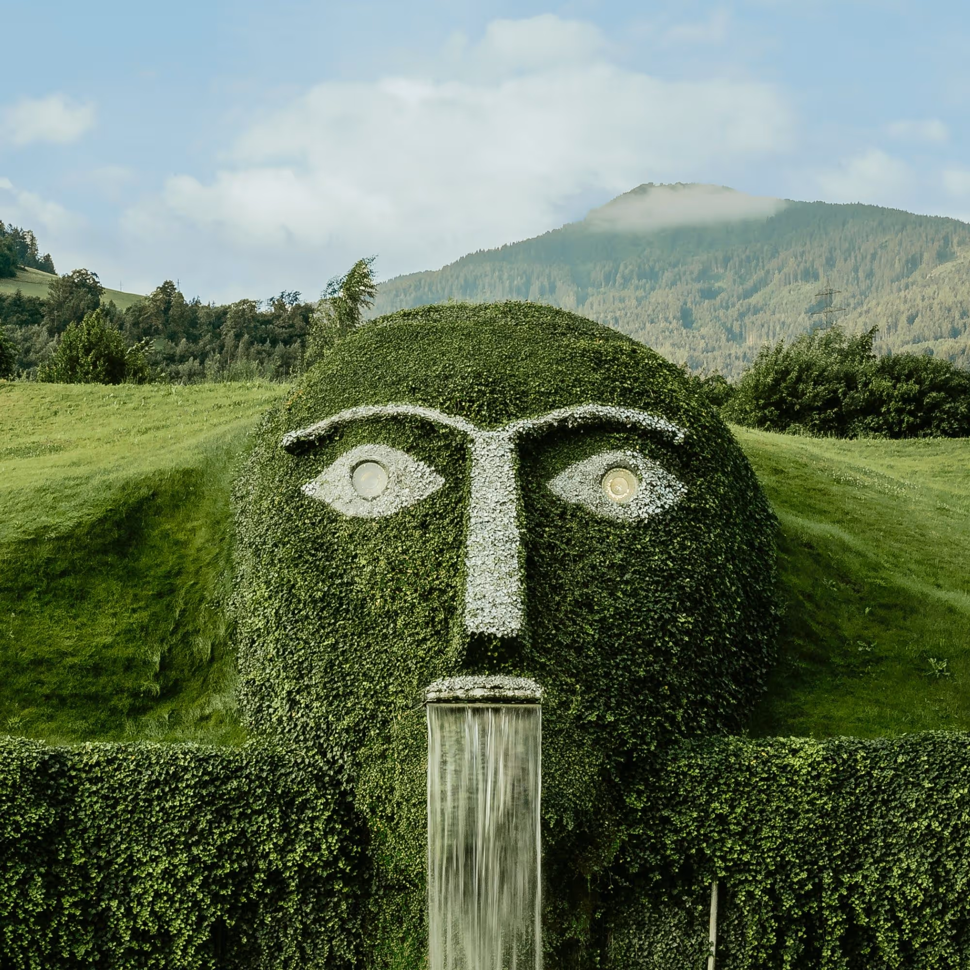 Der markante Riese mit leuchtenden Augen und Wasserfall ist das Herzstück der Swarovski Kristallwelten Wattens, umgeben von der Tiroler Bergkulisse.