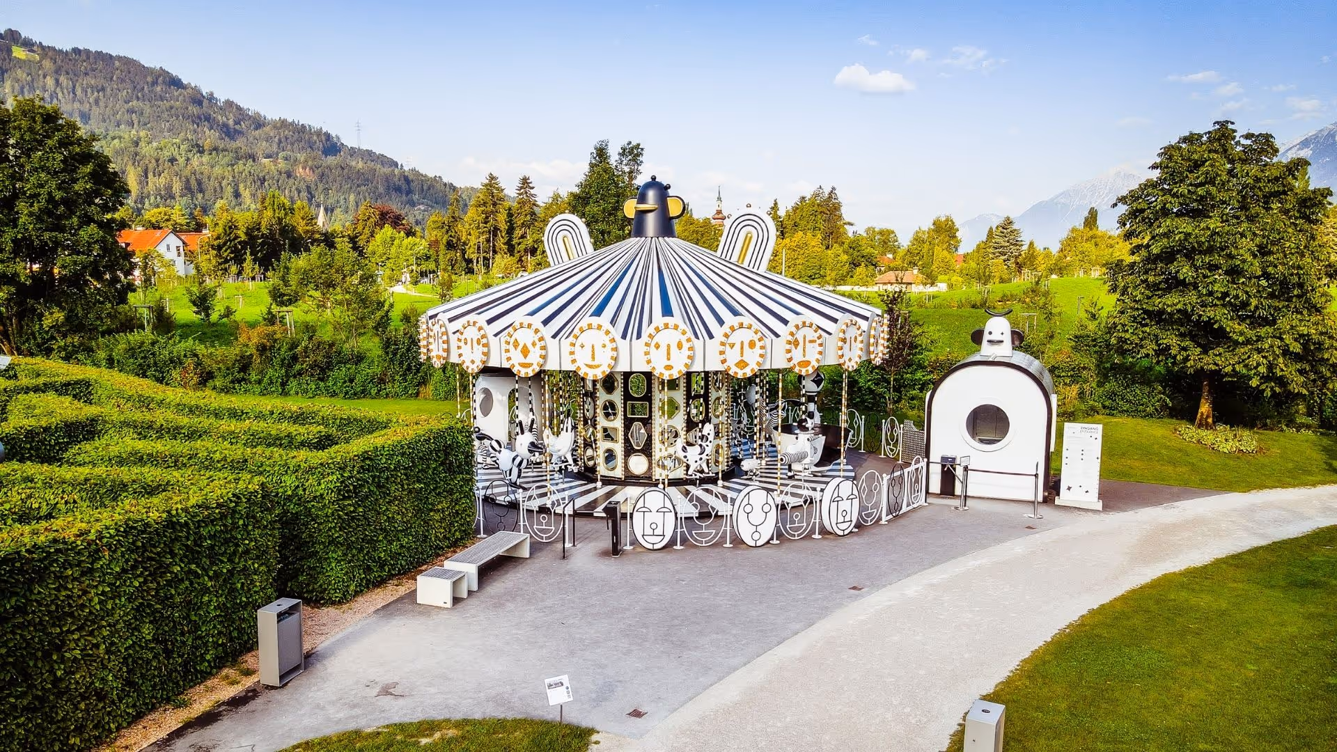 Black and white carousel as a family attraction in the park of Swarovski Kristallwelten, nestled in the Tyrolean mountain scenery.