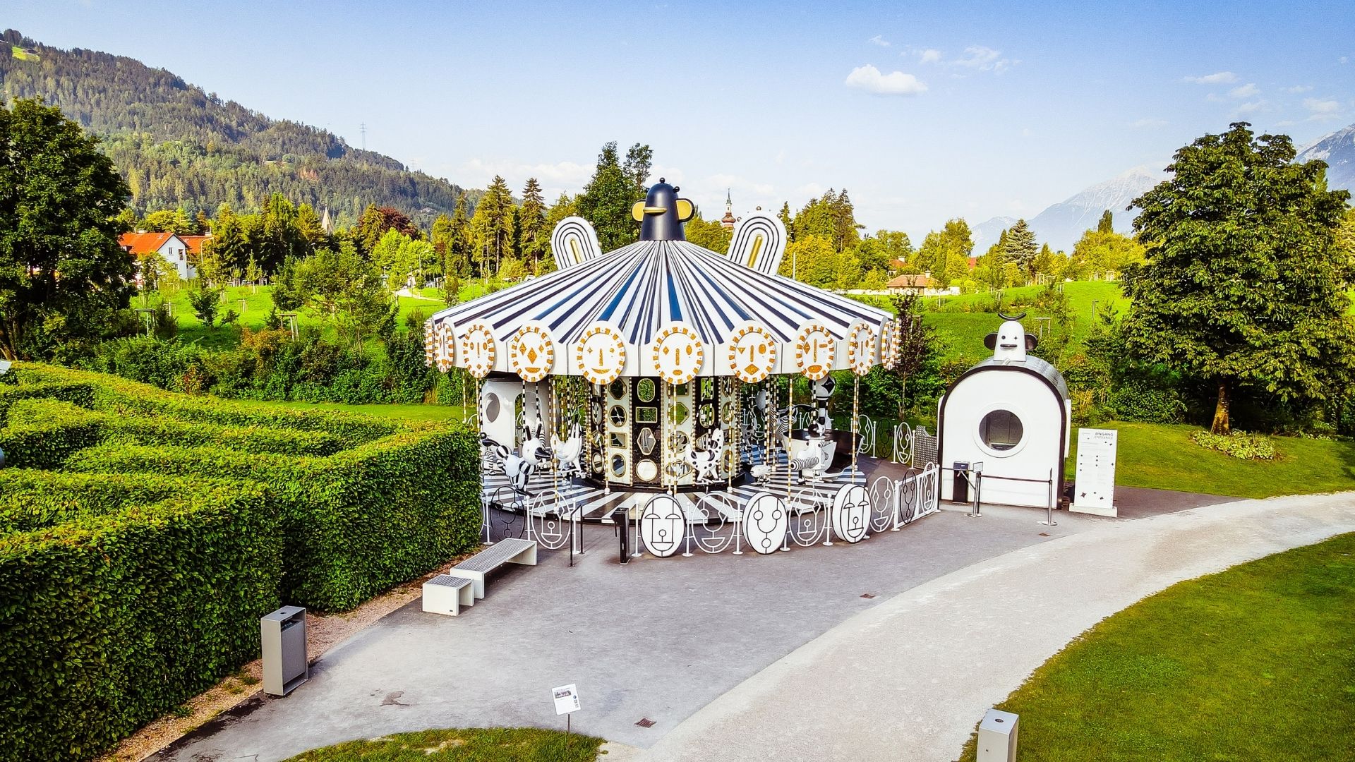 Black and white carousel as a family attraction in the park of Swarovski Kristallwelten, nestled in the Tyrolean mountain scenery.