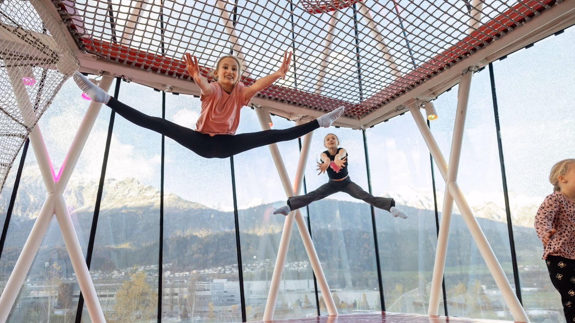 Children jump and frolic in the play tower of Swarovski Kristallwelten — movement and fun with a Tyrolean mountain panorama in the background.