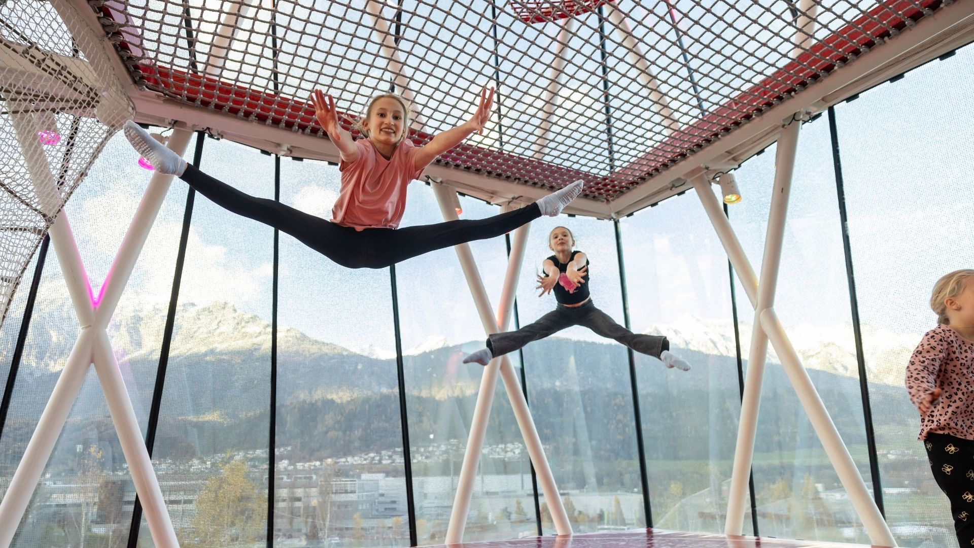 Children jump and frolic in the play tower of Swarovski Kristallwelten — movement and fun with a Tyrolean mountain panorama in the background.