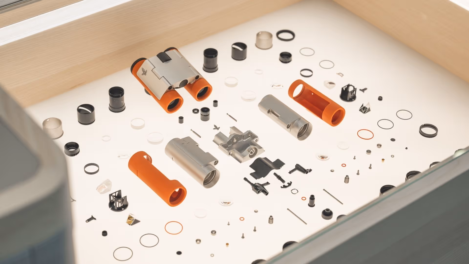 Detailed view of an exhibition case in the Swarovski Optik Store at Swarovski Kristallwelten, showing binoculars disassembled into individual parts with precise components.