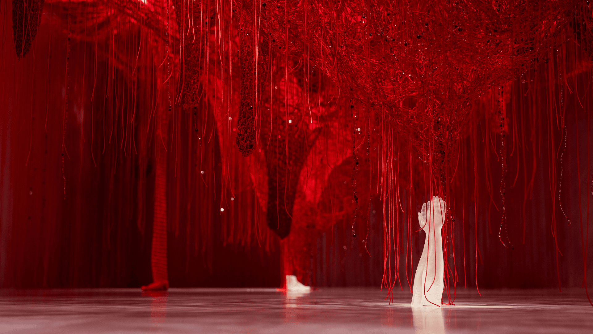 Chamber of Wonder Crystallizing Identity by Chiharu Shiota at Swarovski Kristallwelten: A dense network of red threads with incorporated crystals, from which a white crystal hand rises.