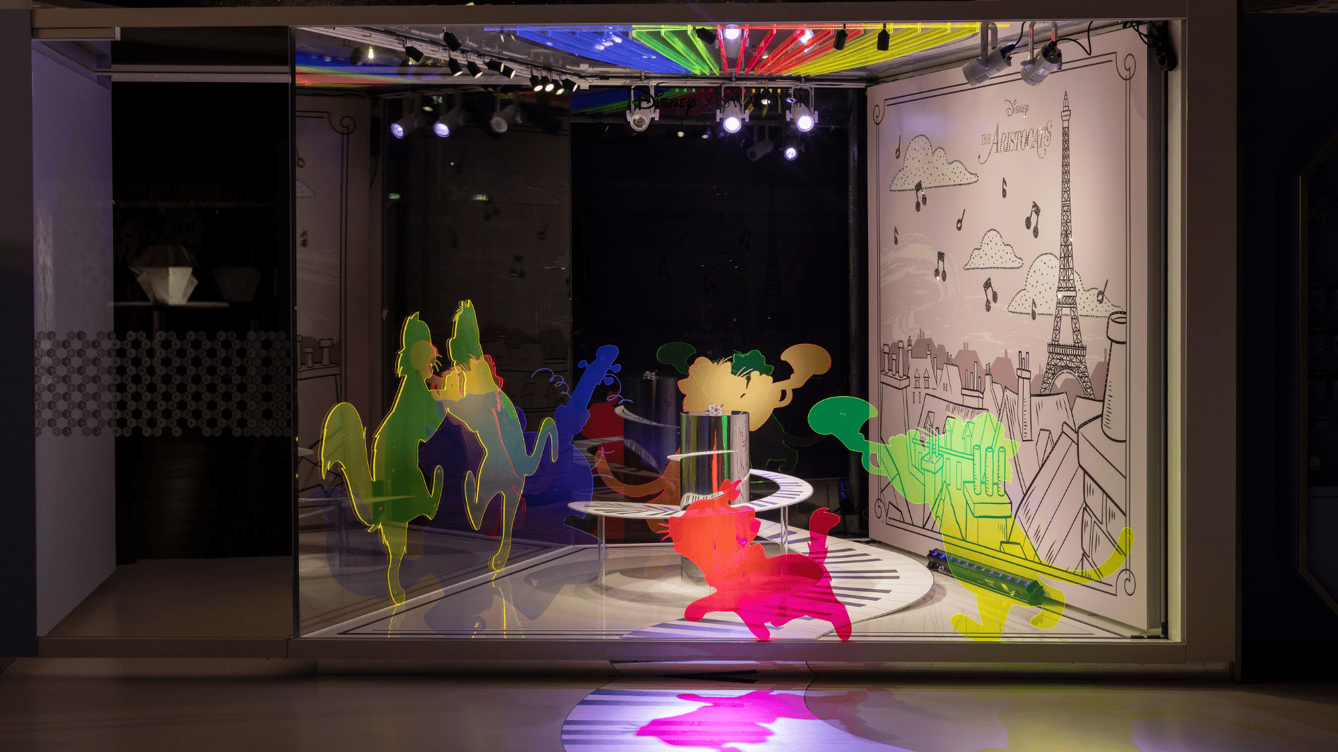 Disney Aristocats Kunstbühne im Swarovski Kristallwelten Store Wattens – leuchtende bunte Katzen-Silhouetten tanzen auf Klaviertasten, begleitet von einem Paris-Hintergrund mit Eiffelturm und Musiknoten.
