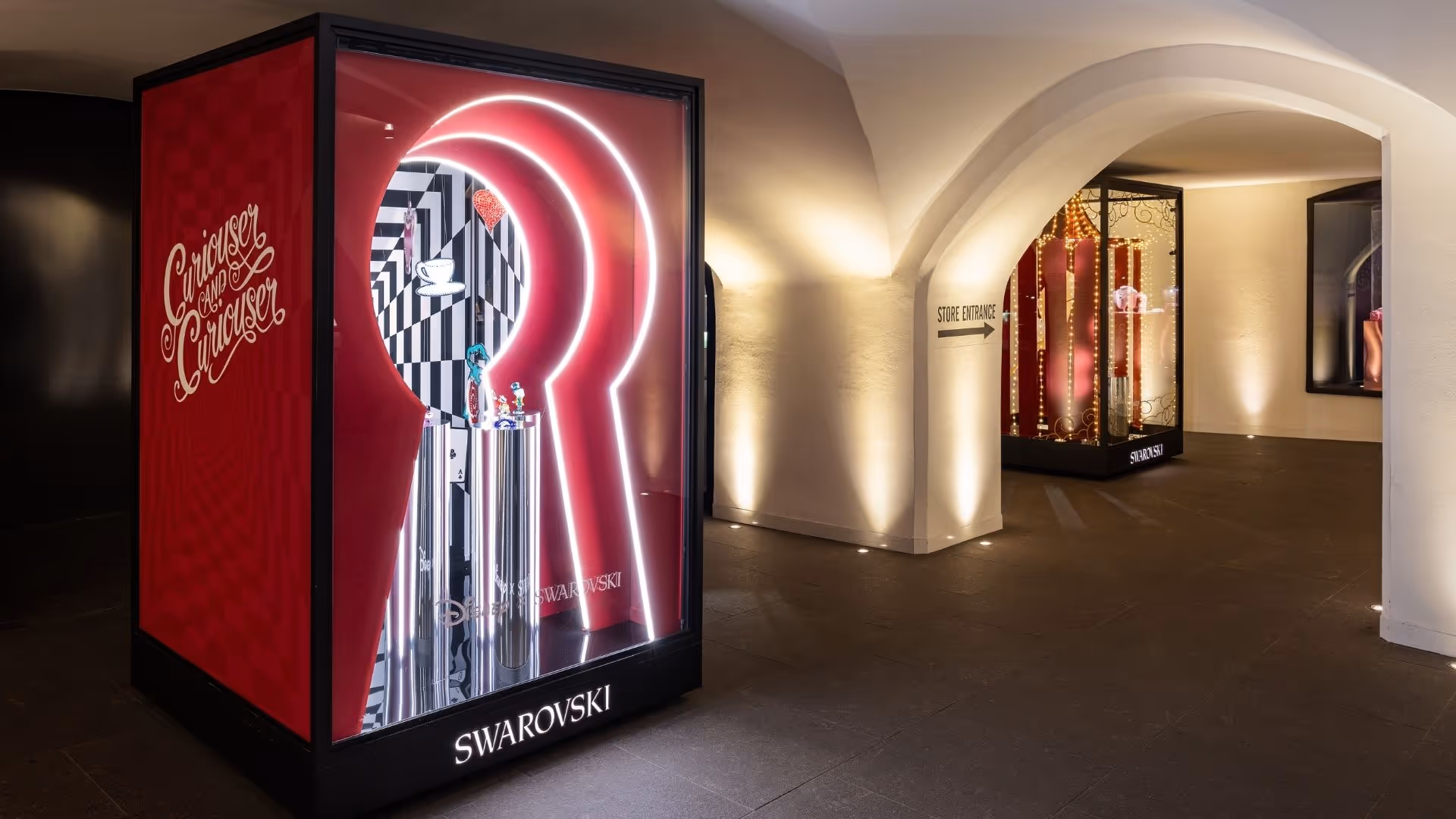 Kunstbühne im Swarovski Kristallwelten Store Innsbruck mit farbenfroher Disney-Inszenierung – beleuchtete Vitrinen zeigen verspielte Kristallfiguren in einer szenischen Gestaltung.