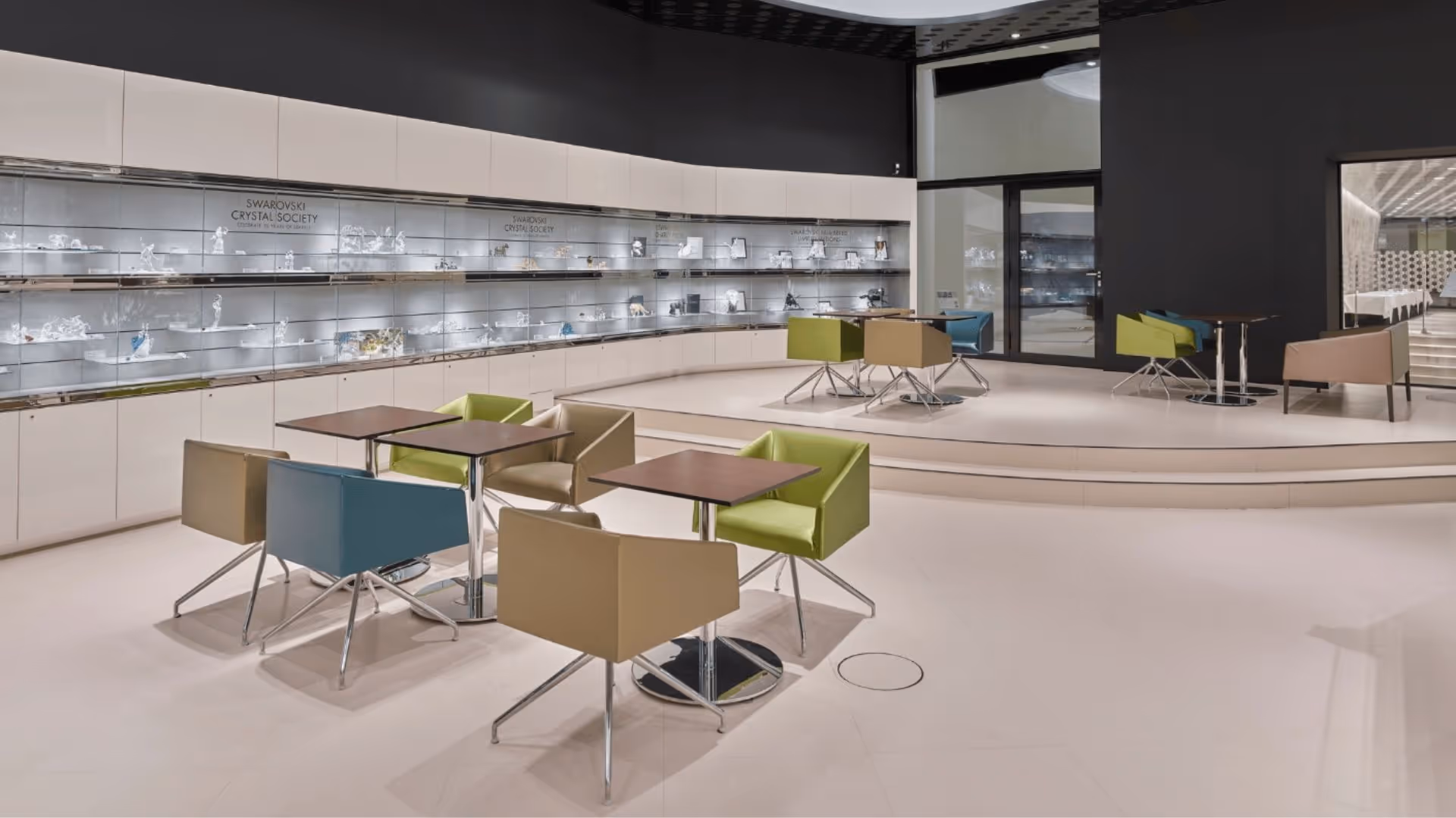 View of the elegant VIP lounge of Swarovski Kristallwelten with a modern seating area and the “Wall of Fame”, where sparkling crystal objects are presented in brightly lit display cases.