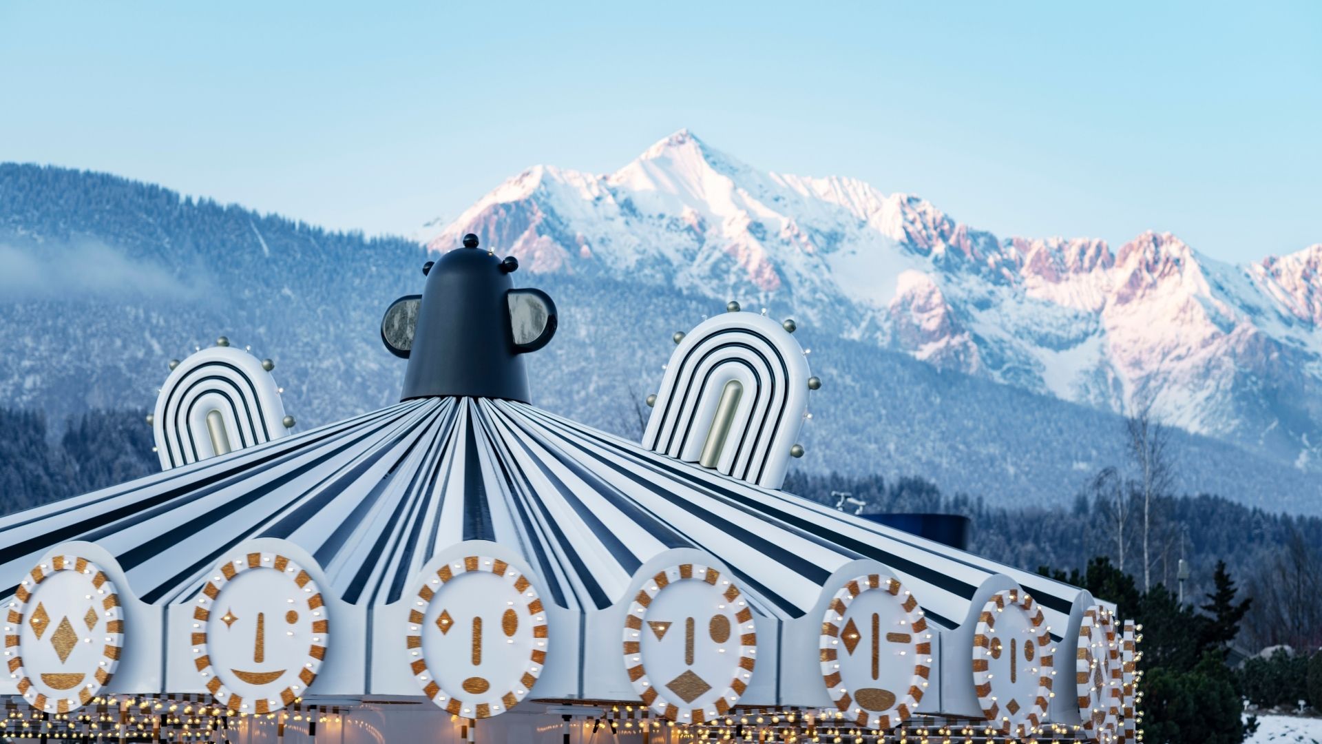 Schwarz-weißes Karussell in den Swarovski Kristallwelten mit verschneiten Bergen im Hintergrund in Wattens, Tirol.