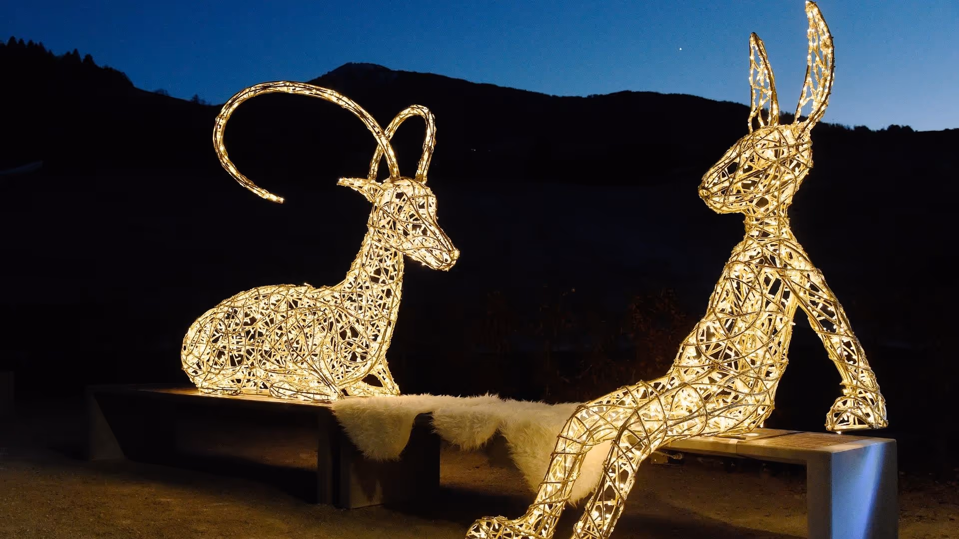 Märchenhafte Lichtinstallation von Tord Boontje –  illuminierter Steinbock und Hase sitzen auf einer Bank im Winter Wonderland der Swarovski Kristallwelten.