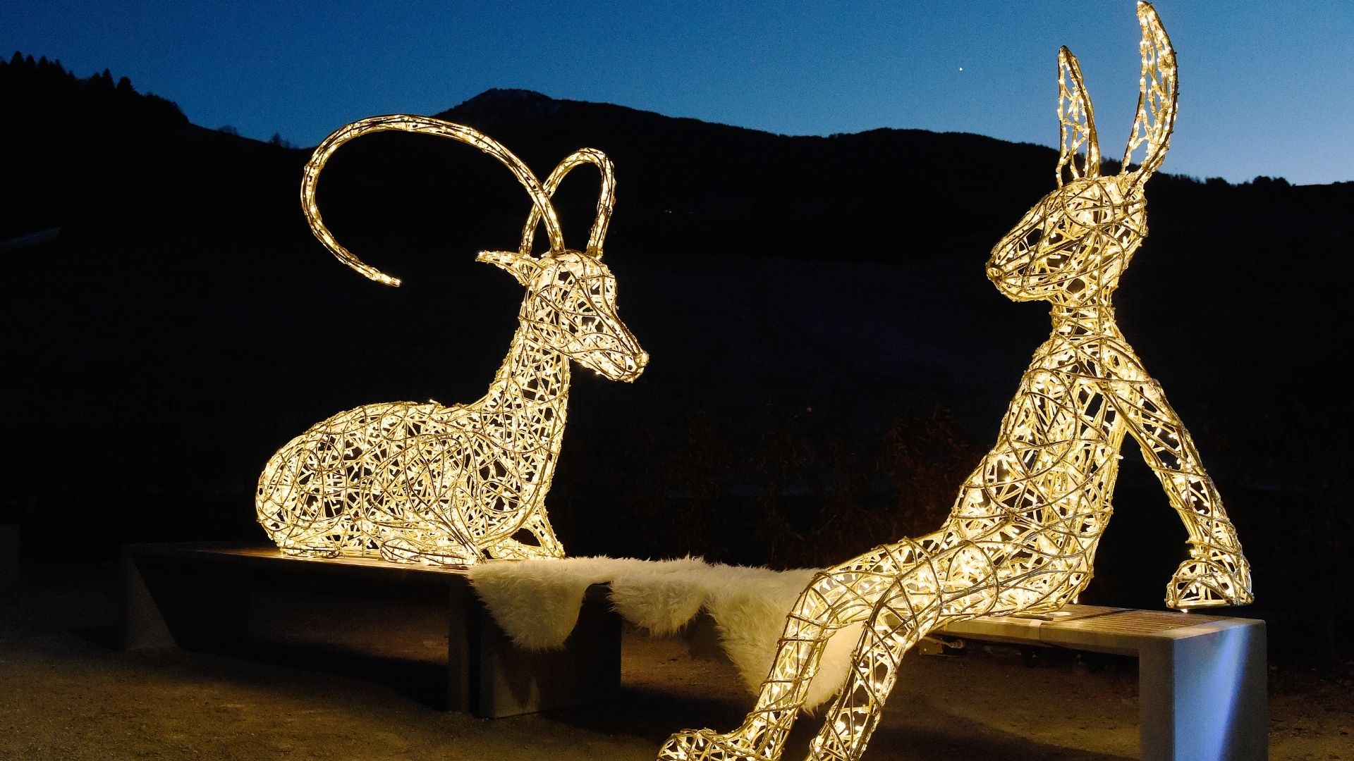 Märchenhafte Lichtinstallation von Tord Boontje –  illuminierter Steinbock und Hase sitzen auf einer Bank im Winter Wonderland der Swarovski Kristallwelten.