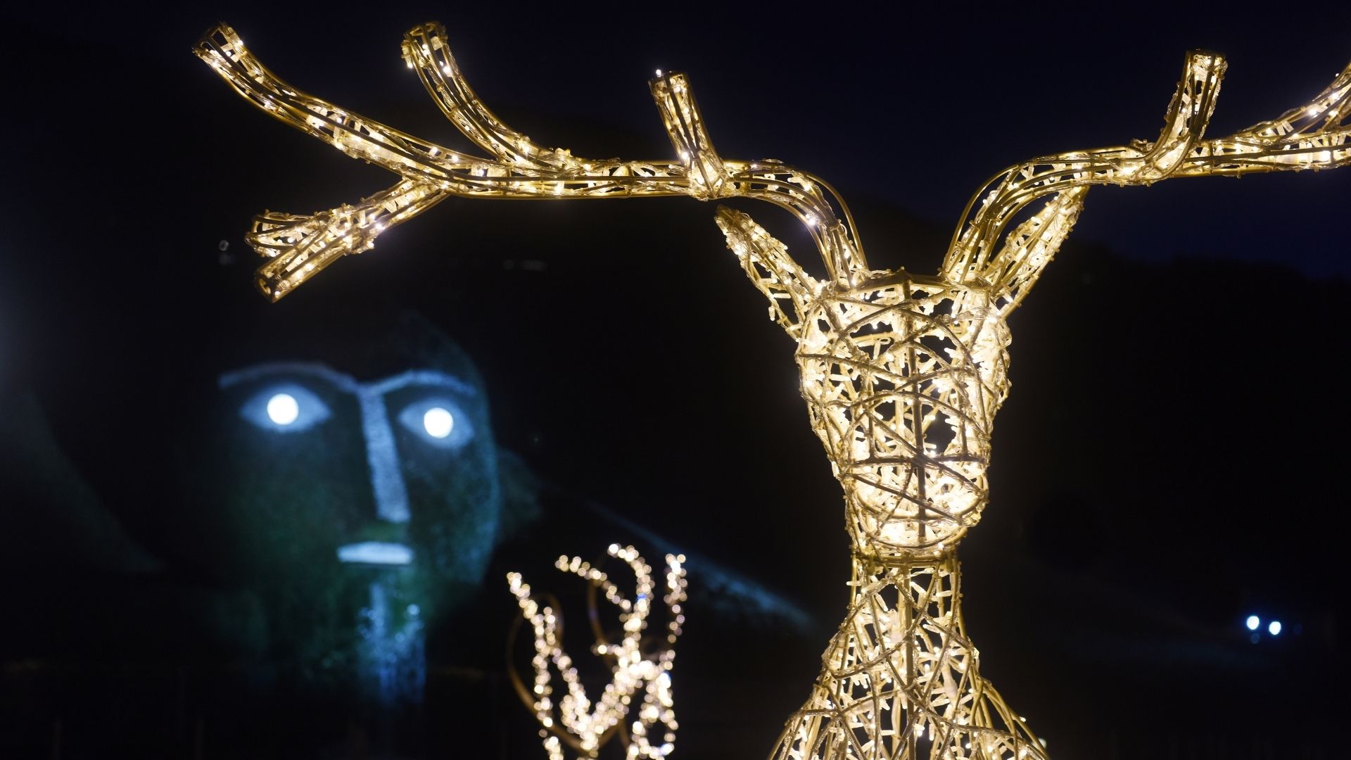 Illuminated deer figure in front of the giant at Swarovski Kristallwelten.
