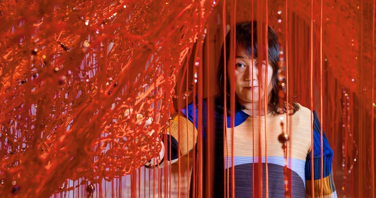 Chiharu Shiota looks through a red thread network with incorporated crystals in her “Crystallizing Identity” Chamber of Wonder at Swarovski Kristallwelten.
