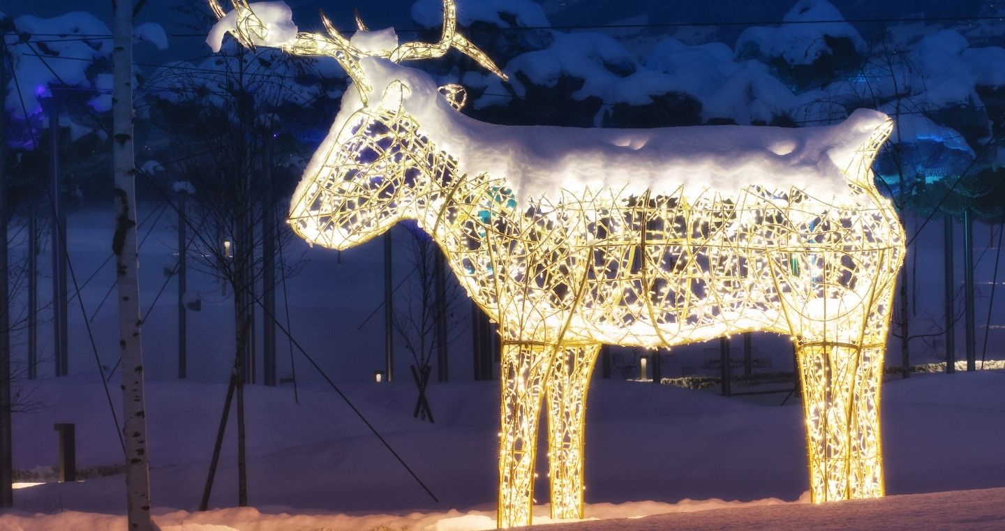 A snow-covered, illuminated reindeer figure glows in the snowy winter landscape of Swarovski Kristallwelten 's Winter Wonderland.