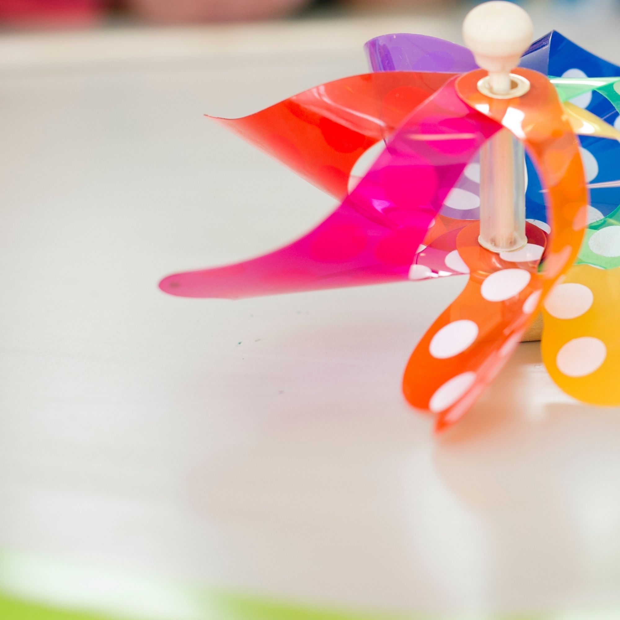 Children's hands make a colorful wind turbine with white dots during a children's program at Swarovski Kristallwelten.