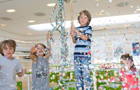 Happy children celebrate with confetti and games during a Swarovski Kristallwelten birthday program.