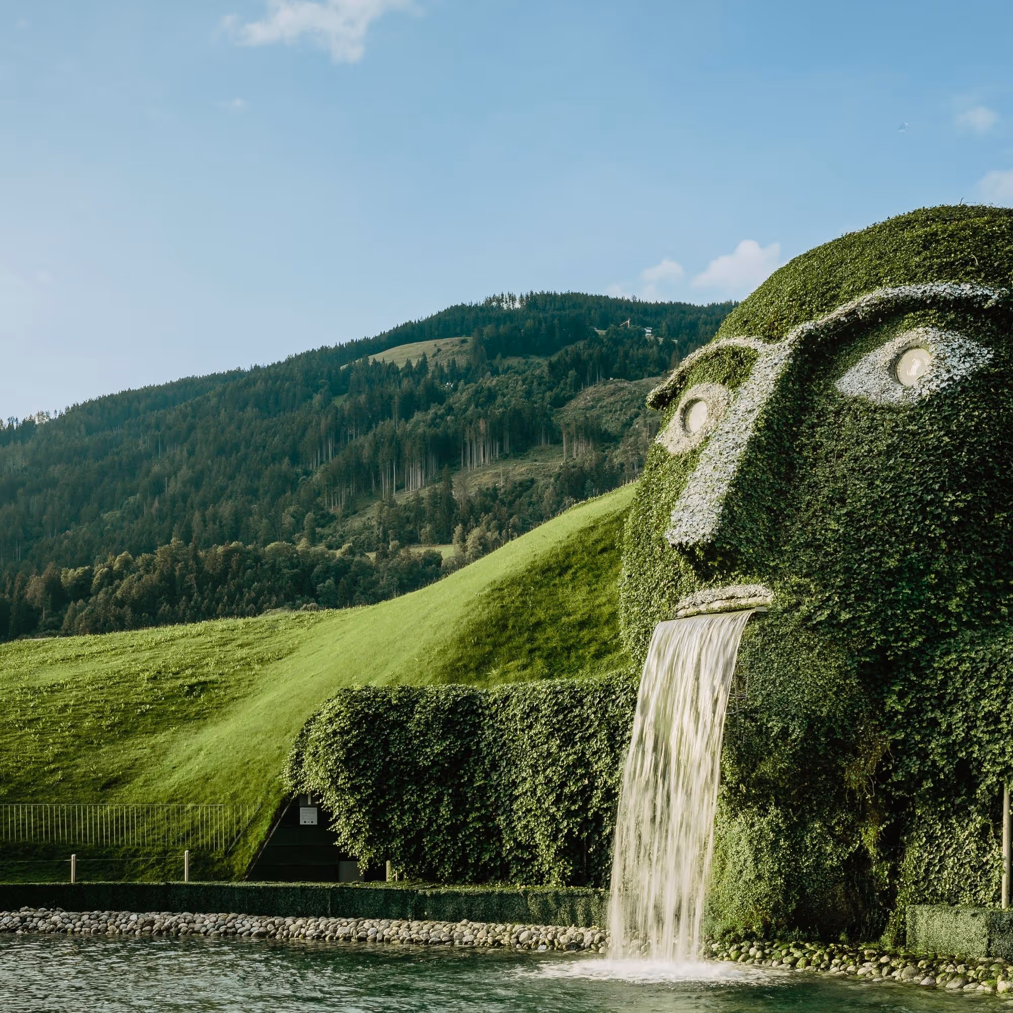 The iconic giant with glowing eyes and waterfall at Swarovski Kristallwelten Wattens, in the midst of the Tyrolean mountain landscape.