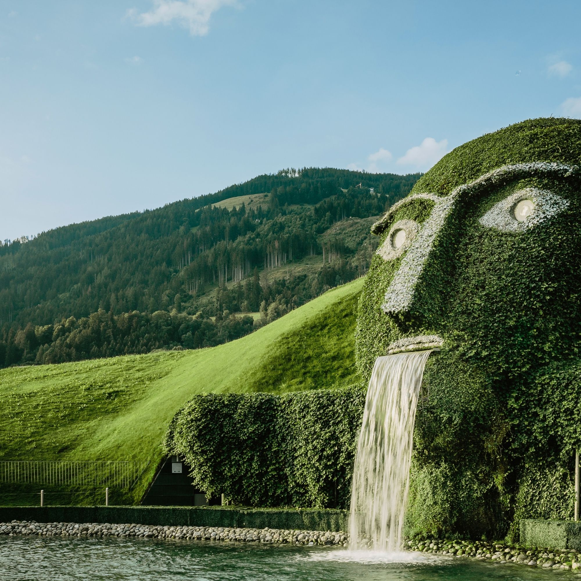 Der ikonische Riese mit leuchtenden Augen und Wasserfall in den Swarovski Kristallwelten Wattens, inmitten der Tiroler Berglandschaft.