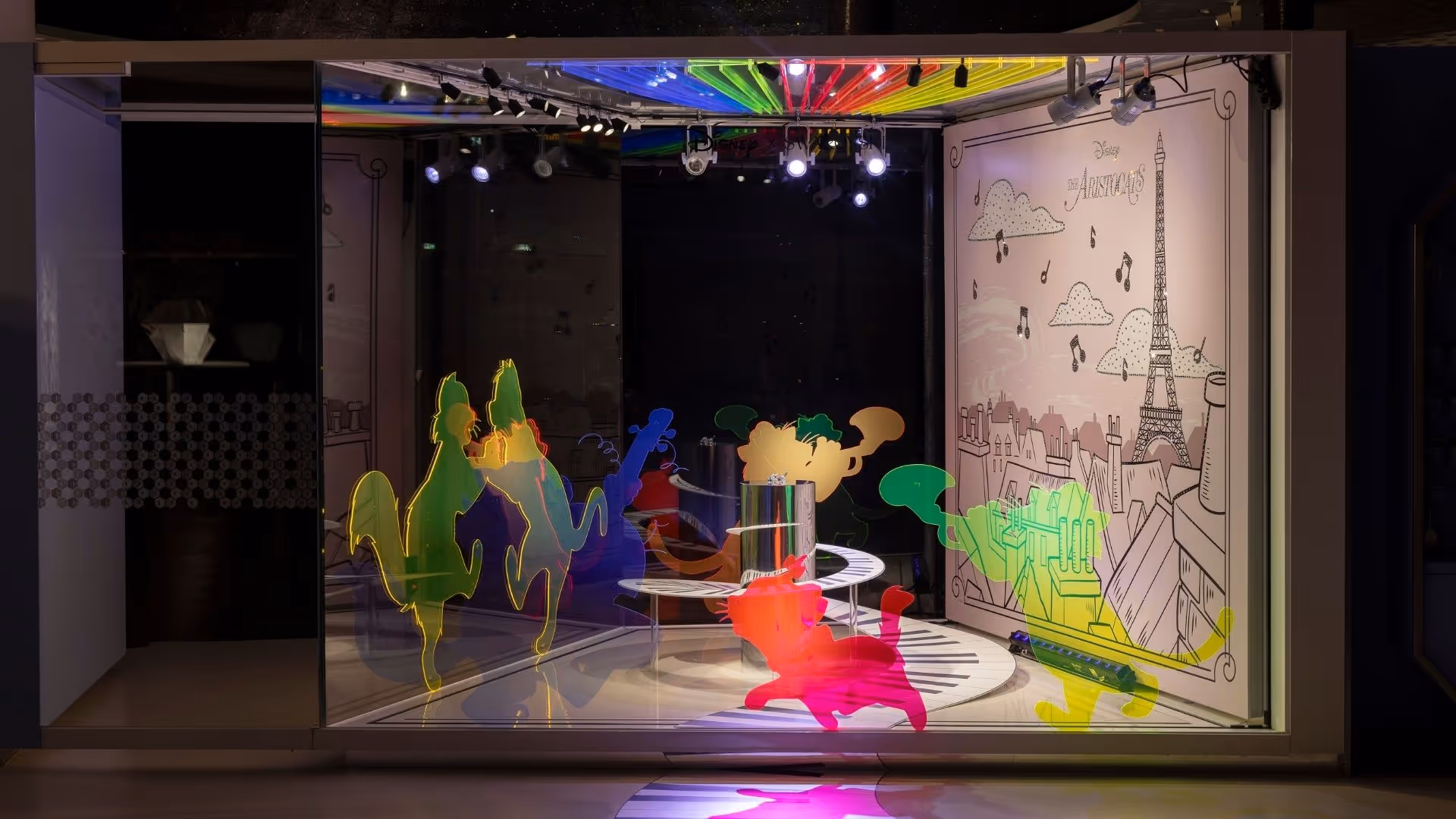 Disney Aristocats Kunstbühne im Swarovski Kristallwelten Store Wattens – leuchtende bunte Katzen-Silhouetten tanzen auf Klaviertasten, begleitet von einem Paris-Hintergrund mit Eiffelturm und Musiknoten.