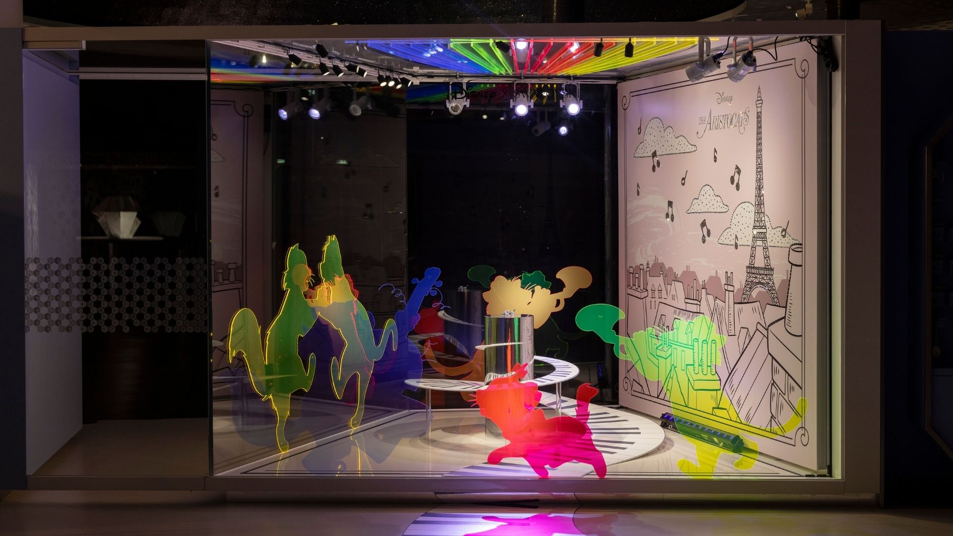 Disney Aristocats art stage at Swarovski Kristallwelten Store Wattens — bright colorful cat silhouettes dance on piano keys, accompanied by a Paris background with an Eiffel Tower and musical notes.