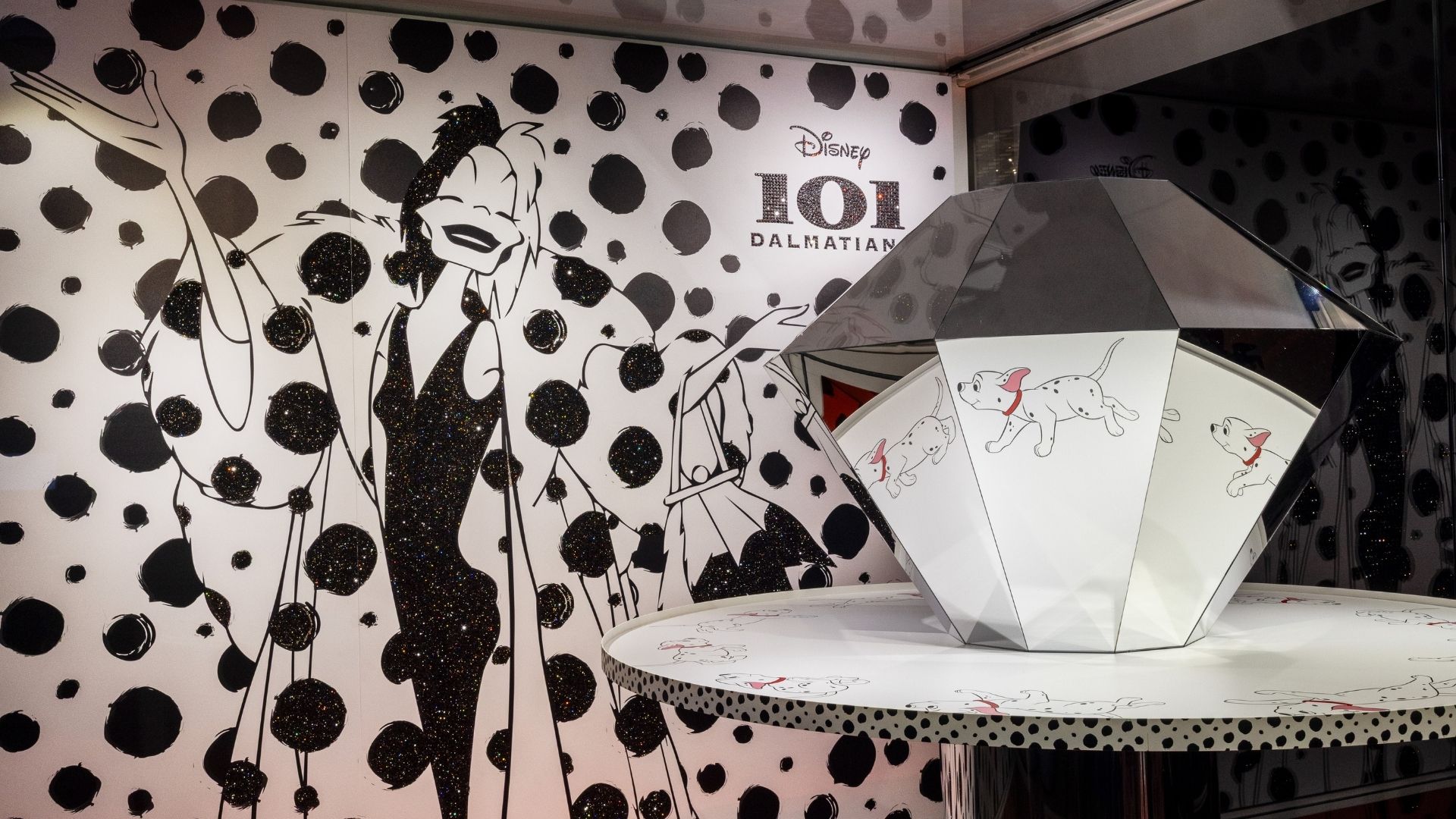 Disney 101 Dalmatiner Kunstbühne im Swarovski Kristallwelten Store Wattens – funkelnde Illustration von Cruella de Vil vor schwarz-weißem Punktedesign und Praxinoskop mit Dalmatiner-Motiven.