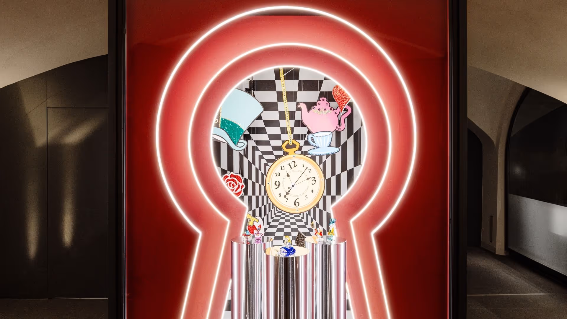 Alice im Wunderland Kunstbühne im Swarovski Kristallwelten Store Innsbruck – Blick durch ein leuchtendes Schlüsselloch auf eine Inszenierung mit Uhr, Teekanne, Hut, Rose und funkelnden Kristallfiguren vor schwarz-weißem Schachbrett-Hintergrund.
