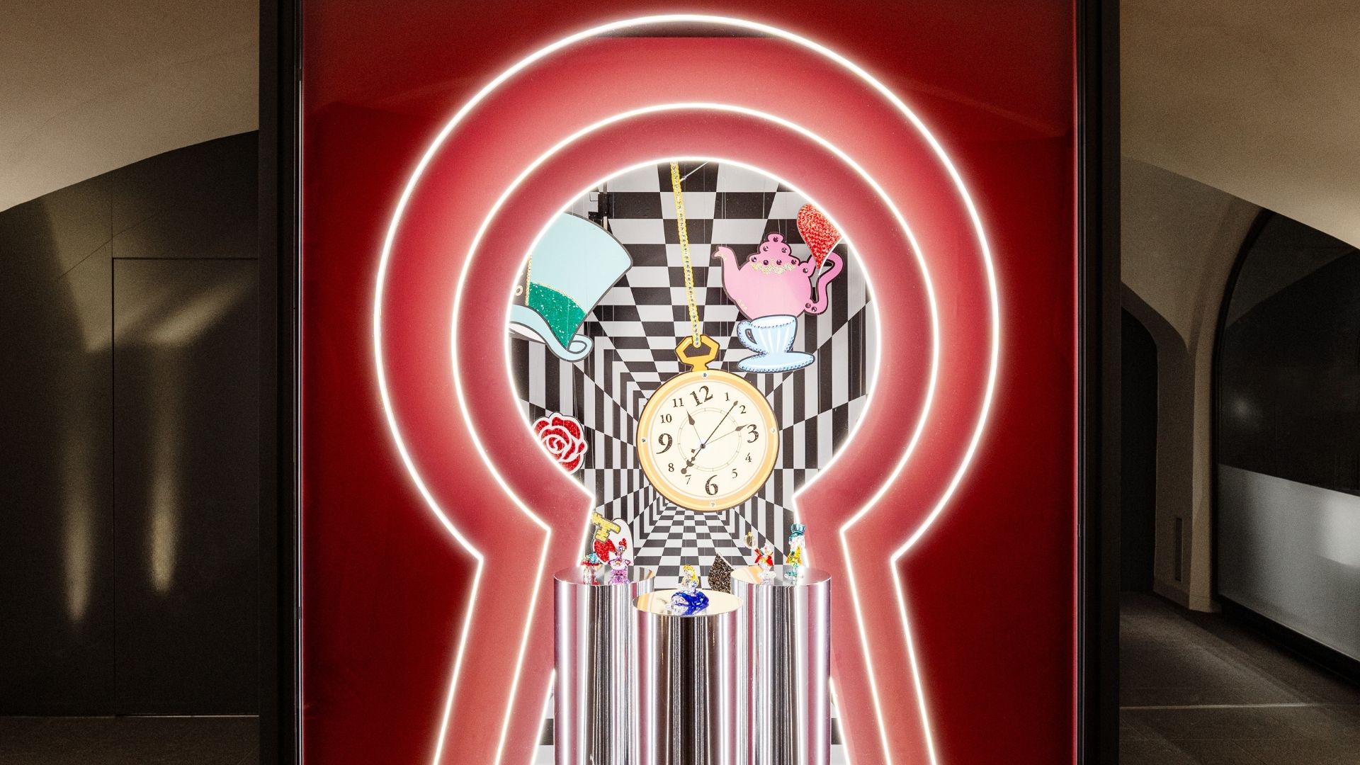 Alice in Wonderland art stage at Swarovski Kristallwelten Store Innsbruck — View through a glowing keyhole at a production with clock, teapot, hat, rose and sparkling crystal figures against a black and white checkerboard background.
