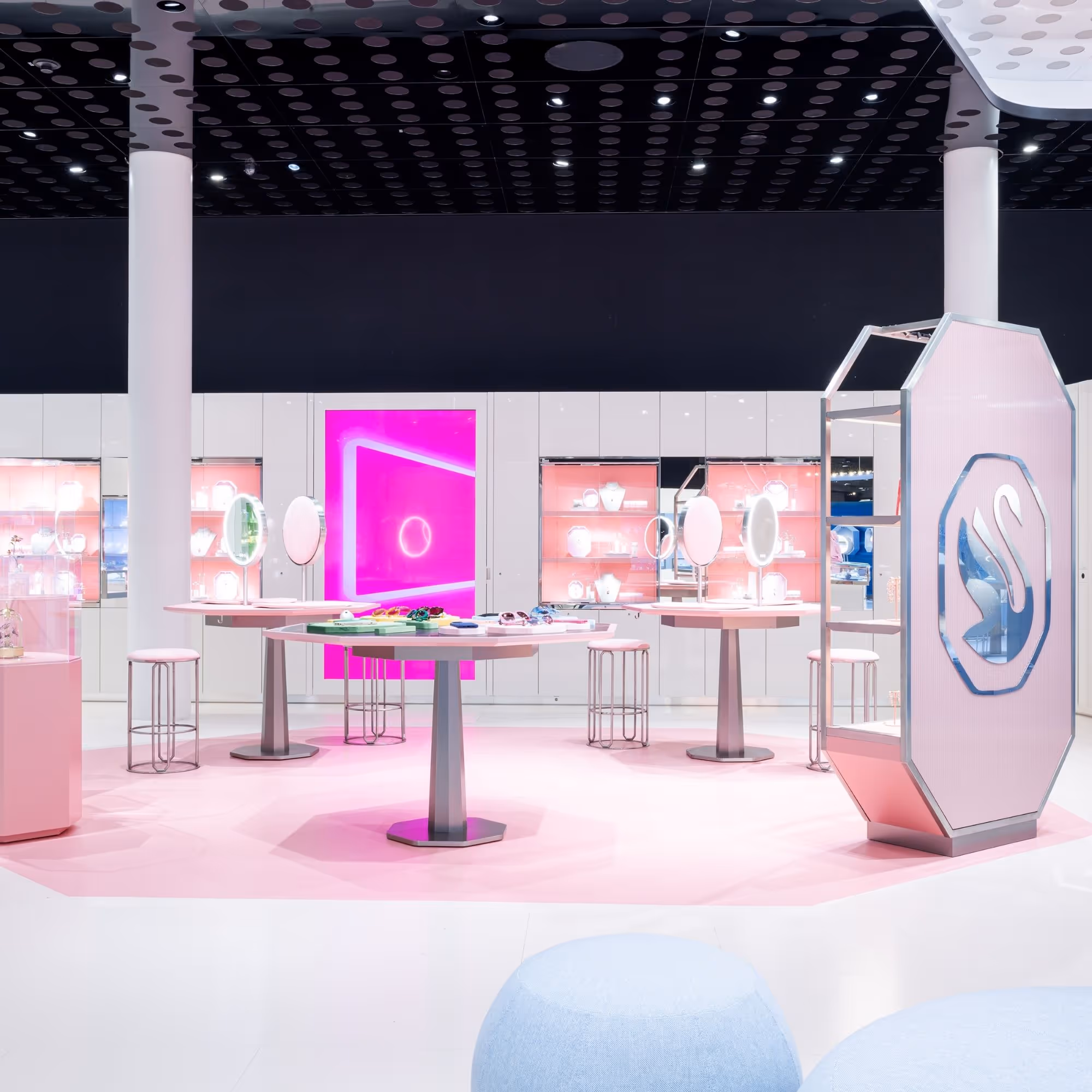 Interior view of the Swarovski Kristallwelten Store Wattens: modern retail space with white furniture, pink accents, glowing presentation islands and display cases full of jewelry.