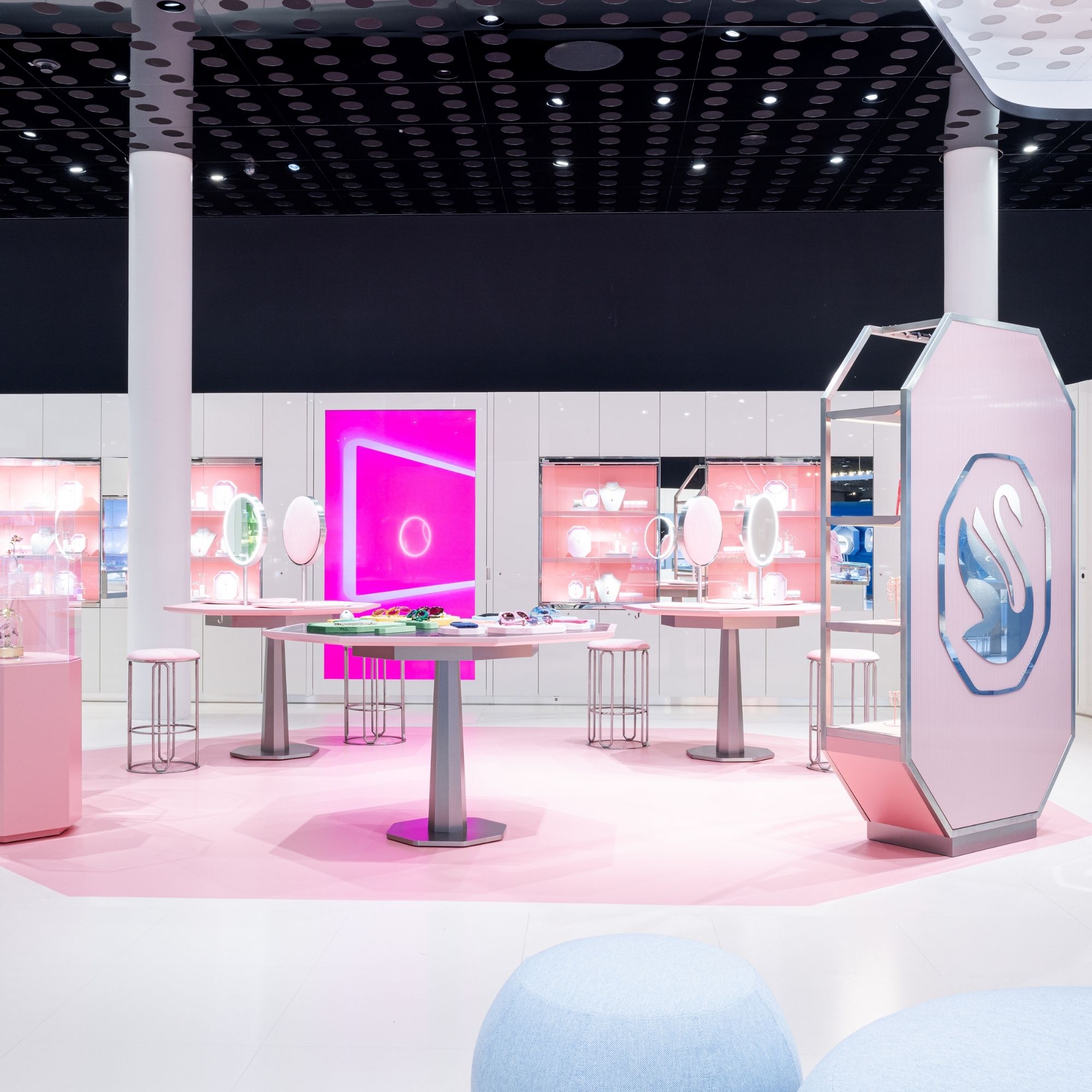 Innenansicht des Swarovski Kristallwelten Stores in Wattens: moderne Verkaufsfläche mit weißen Möbeln, rosa Akzenten, leuchtenden Präsentationsinseln und Vitrinen voller Schmuckstücke.
