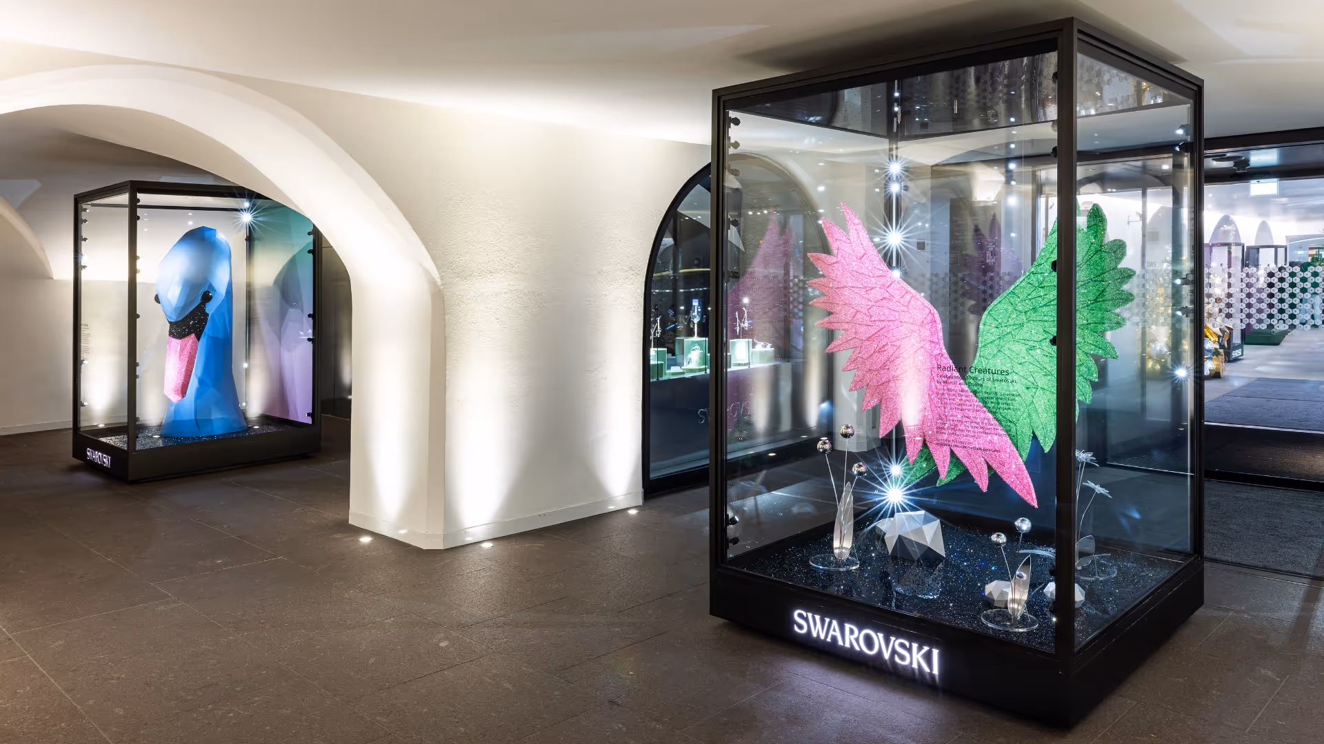 A larger-than-life crystal swan head in blue sits inside an outdoor store showcase. 