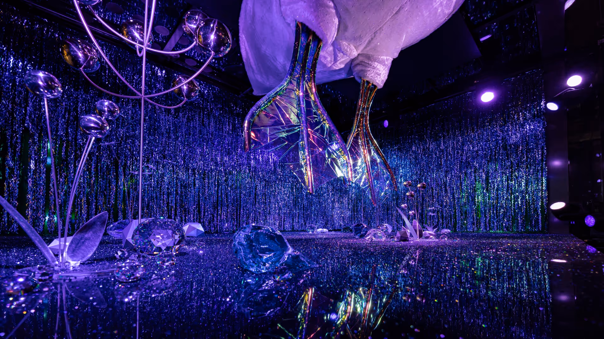 In the window of Swarovski Kristallwelten Store Wien, facing busy Kärntner Straße, two blue crystal swan feet come down from the ceiling of the window
and move slowly as if the animal was alive, swimming smoothly in the water. The window wall and floor are covered with faceted metallic surface. Mirrored flowers and faceted stones complete this sharp and frozen environment. The walls and floor of the shop window in faceted metal frame the picture. The mirror flowers and faceted pebbles perfectly round off this bitterly cold backdrop. The walls and floor of the shop window in faceted metal frame the picture. The mirror flowers and faceted pebbles perfectly round off this bitterly cold backdrop. and move slowly as if the animal was alive, swimming smoothly in the water.
The window wall and floor are covered with faceted metallic surface. Mirrored flowers and faceted stones complete this sharp and frozen environment. The walls and floor of the shop window in faceted metal frame the picture. The mirror flowers and faceted pebbles perfectly round off this bitterly cold backdrop. 