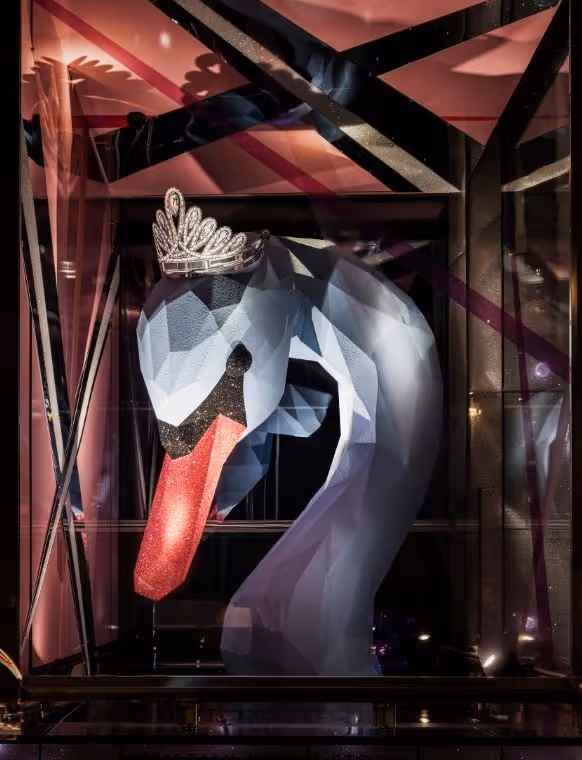 In the top cube of Swarovski Kristallwelten Store Wien, facing busy Kärntner Straße, a larger-than-life head of a swan, covered in white feathers, is seen wearing the Swarovski Vienna Opera Ball Tiara 2025.