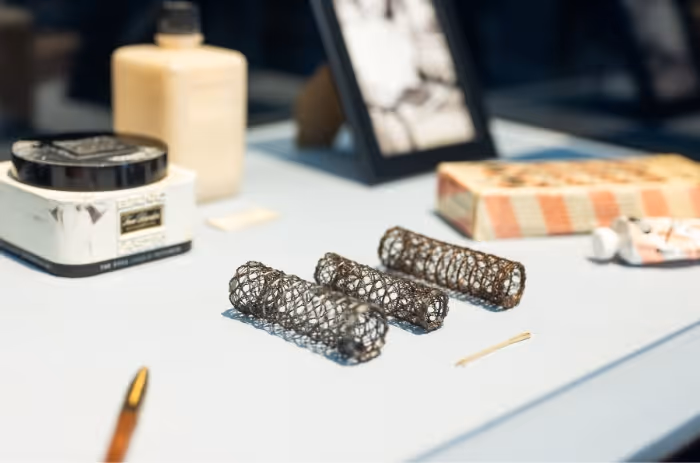 Vintage-Accessoires auf Tisch: drei Metall-Haarwickler, Cremedosen und gerahmtes Foto im Hintergrund.