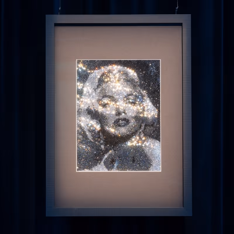 Gerahmtes Kunstwerk mit Porträt von Marilyn Monroe, aus zahlreichen Kristallen zusammengesetzt, vor dunklem, beleuchtetem Hintergrund.