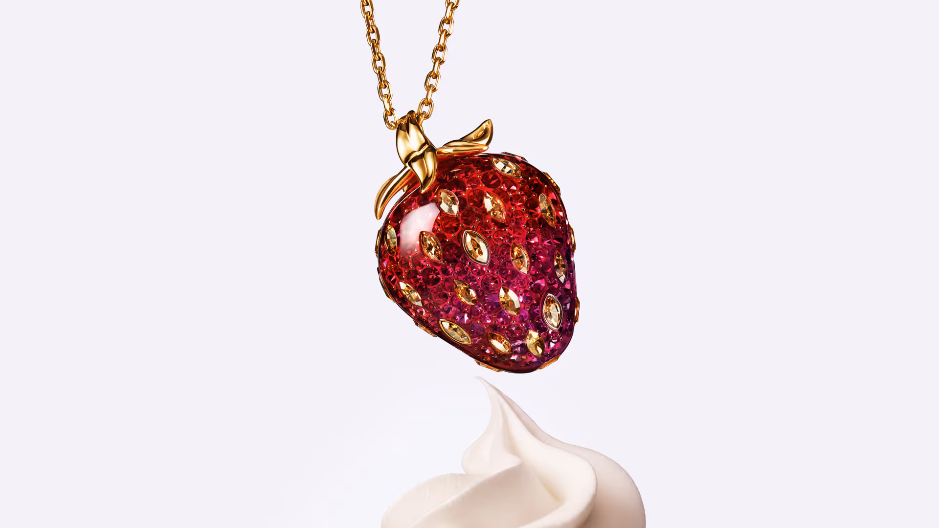 Swarovski necklace with strawberry pendant made of red and gold crystals, detailed, against a light background with decorative cream dot.