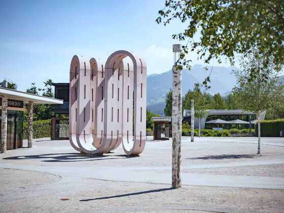 Kunstwerk 'Conveyor Belt': Große rosafarbene Skulptur im Freien, bestehend aus geschwungenen, organischen Formen.