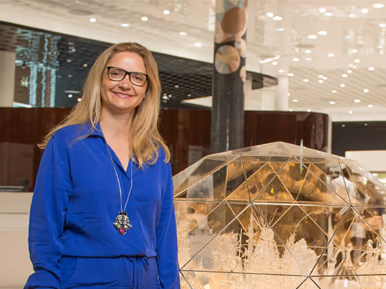 Melli Ink, deutsche Künstlerin, 2016 im blauen Outfit, stehend neben ihrem Kunstwerk im Swarovski Kristallwelten Store.