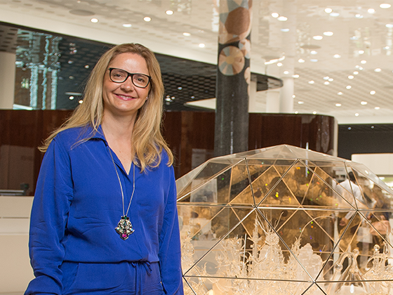 Melli Ink, deutsche Künstlerin, 2016 im blauen Outfit, stehend neben ihrem Kunstwerk im Swarovski Kristallwelten Store.