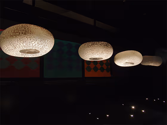 John Brekke, 2004 – Kunstwerk mit leuchtenden Lampenschirmen, die mit Textmustern versehen sind.