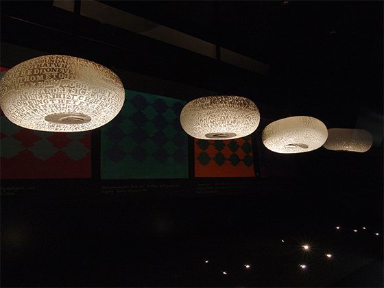 John Brekke, 2004 – Kunstwerk mit leuchtenden Lampenschirmen, die mit Textmustern versehen sind.
