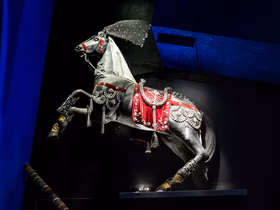 Ein detailreich dekoriertes Pferd von Philippe Ferrandis, verziert mit funkelnden Swarovski-Kristallen und roten Ornamenten. Das Pferd steht aufrecht auf den Hinterbeinen und wirkt majestätisch.