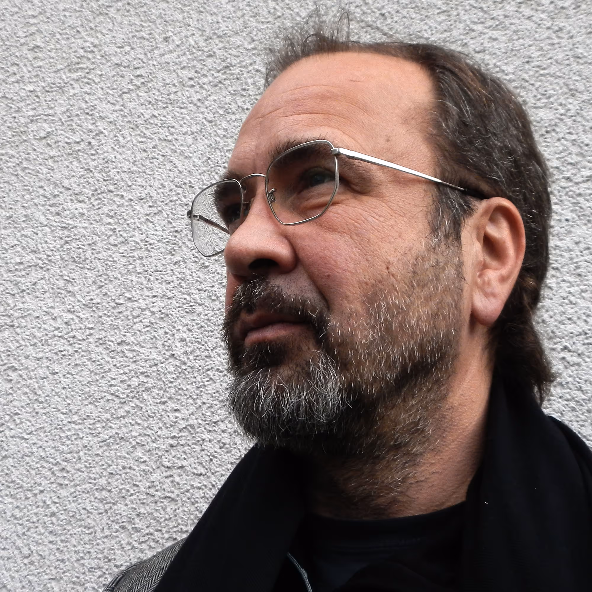 Martin Gostner, österreichischer Künstler, 2014 im Porträt mit grauem Hintergrund, ernster Gesichtsausdruck.