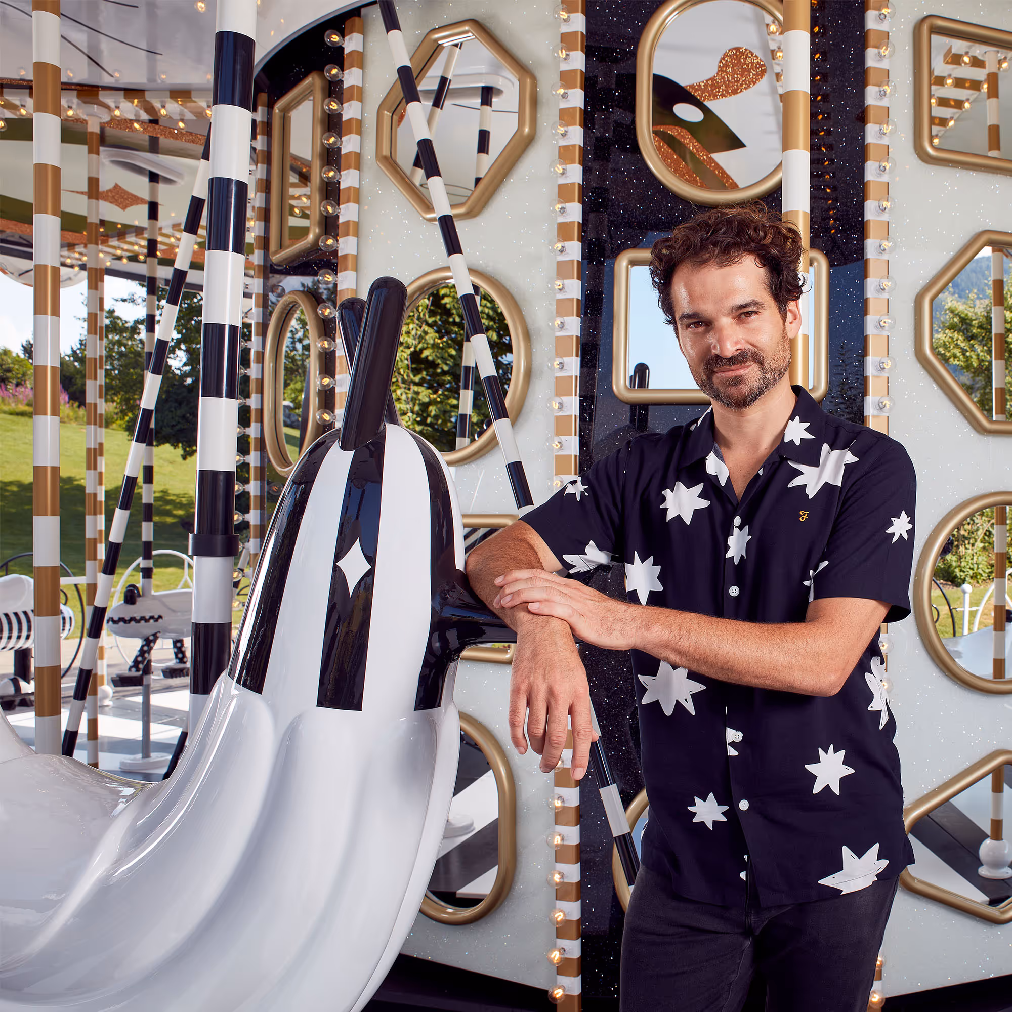 Jaime Hayon, spanischer Designer, 2019 in auffälliger Sternenbluse, lachend vor seiner Karussell-Installation.