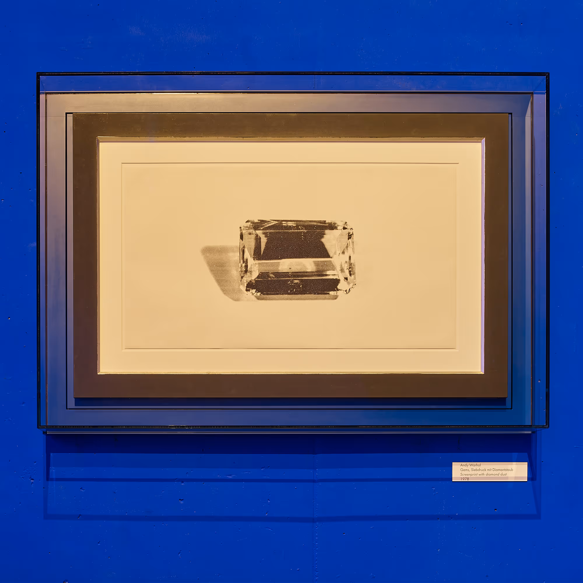 Andy Warhol, 2017 – Schwarz-weiße Grafik eines geschliffenen Kristalls in einem schlichten Rahmen, ausgestellt vor einer kräftig blauen Wand.